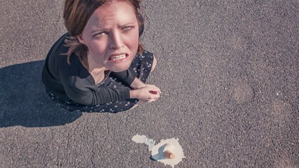 A woman, angry at herself, for dropping her ice-cream on the floor