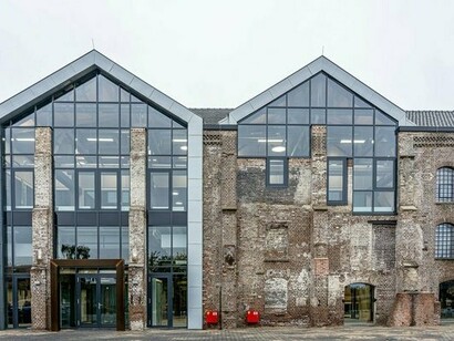 An old brick warehouse reimagined with expansive glass structures, representing the evolution of adaptive reuse