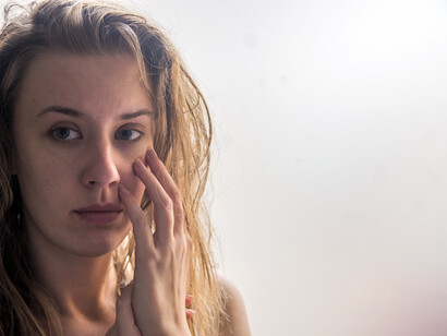 Donna con un'espressione triste e malinconica, una mano le sfiora il viso