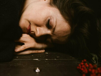 Mulher sofre enquanto observa aliança no chão. Talvez esteja apenas na crise dos quase 30 anos, apesar do meu lado racional reconhecer as pequenas vitórias que antes via apenas como obrigações, me vejo presa nas coisas que eu não tenho, nos sonhos desmanchados, da dureza da vida adulta, da solidão que a mesma trás