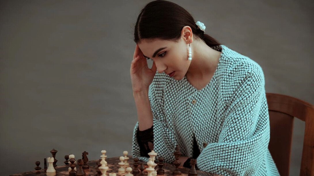A contemplative woman of diverse ethnicity pondering her next chess move