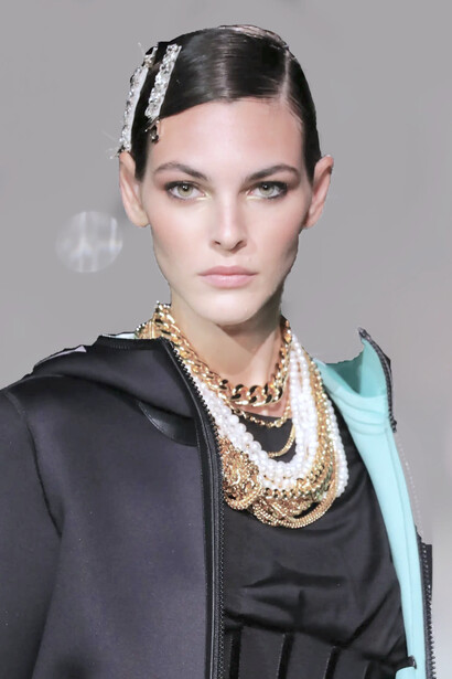 Modelo utiliza colares de pérolas e correntes de ouro, além de fivelas com detalhes prateados no cabelo