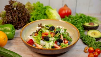 A vibrant vegetable salad presented in an earthy brown ceramic bowl