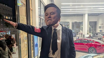 Manifestante faz referência ao gesto de Elon Musk durante a posse de Donald Trump. Ao realizar uma saudação nazista, Musk não apenas chocou o mundo, mas também reforçou a normalização de símbolos históricos de opressão, violência e autoritarismo. Musk gerou repercussões globais, incentivando extremistas ao redor do mundo e alimentando a retórica de grupos neonazistas, que enxergaram naquele ato uma validação de suas crenças. Não houve, porém, nenhuma responsabilização por seu ato
