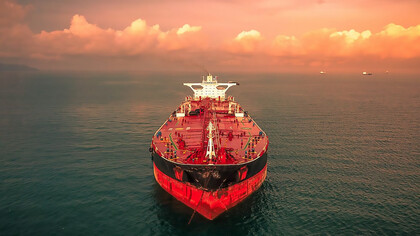 The red and white cargo ship Merlion M sails under a cloudy sky off the coast of Johor, Malaysia