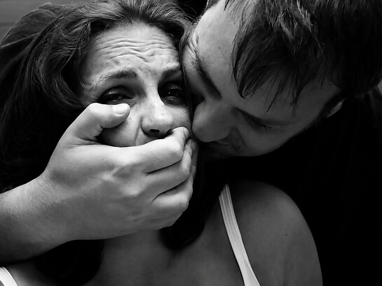 A violent scene depicting a man restraining a woman and covering her mouth during a physical assault